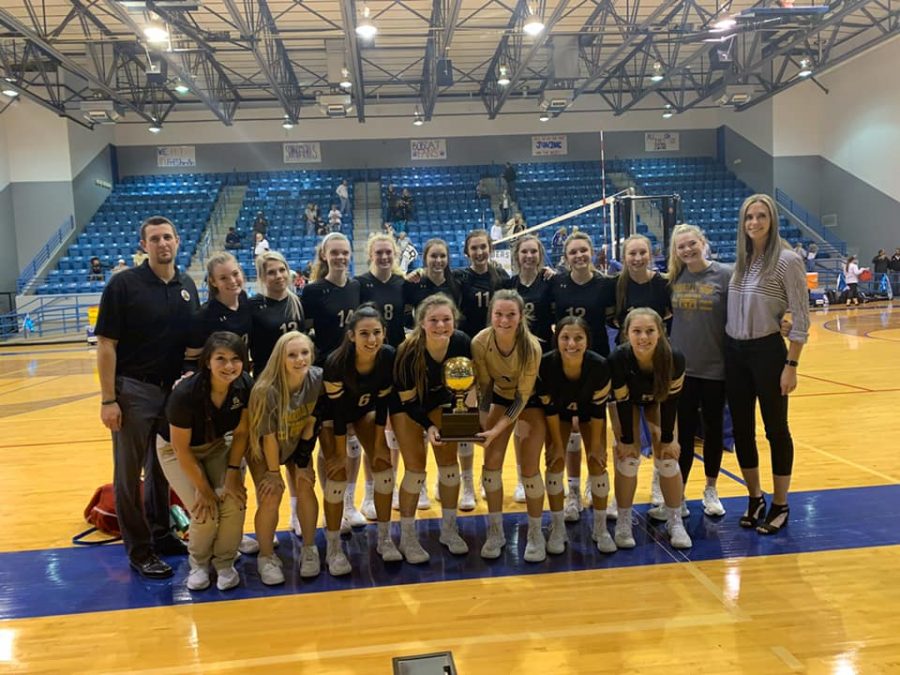 The volleyball team gathers around thier Bi-District trophy